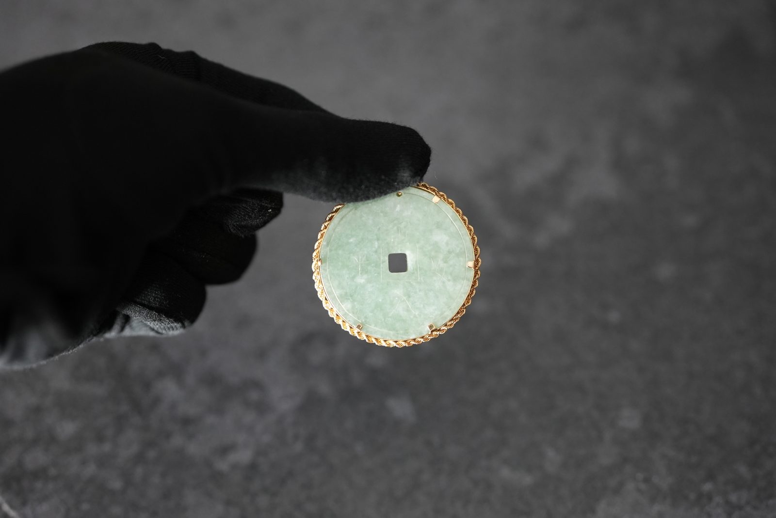 Carved jade disc pendant — in hand